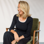 Picture o Valerie Beauséjour sitting on a vintage chair smiling.