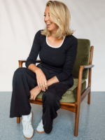 Picture of Valerie Beauséjour sitting in a vintage green couch smiling.