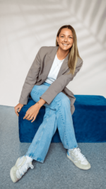 Stéphanie Gendron sitting in a rectangle blue pouf smiling.