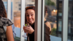 A woman smiling at the camera, holding a drink with a lime garnish at an event.