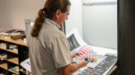 A man reviewing printed materials and colour swatches in a workspace, focusing on quality control.